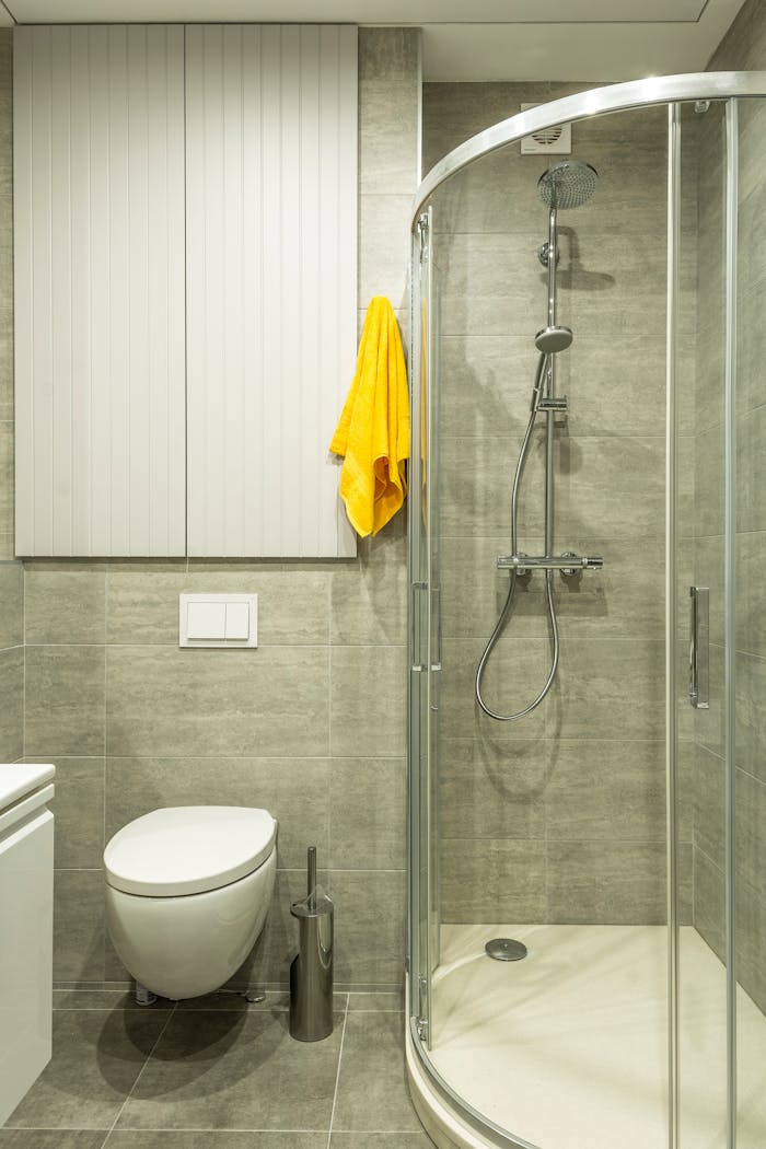 services-img-01 Bright modern bathroom featuring a shower cabin, toilet, and yellow towel for a clean look.